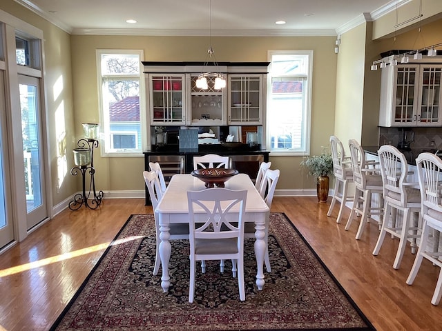 dining space with a chandelier, hardwood / wood-style flooring, and ornamental molding