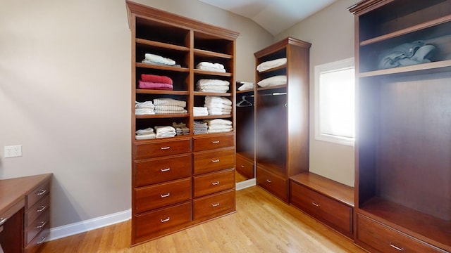 spacious closet with light hardwood / wood-style flooring and vaulted ceiling