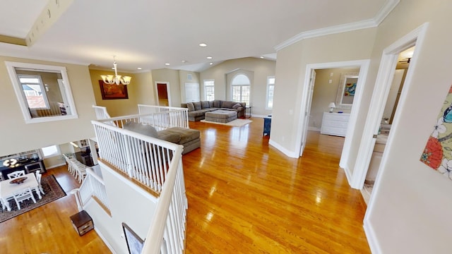 hallway featuring hardwood / wood-style flooring, a notable chandelier, ornamental molding, and plenty of natural light