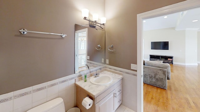 bathroom with hardwood / wood-style flooring, tile walls, toilet, and vanity