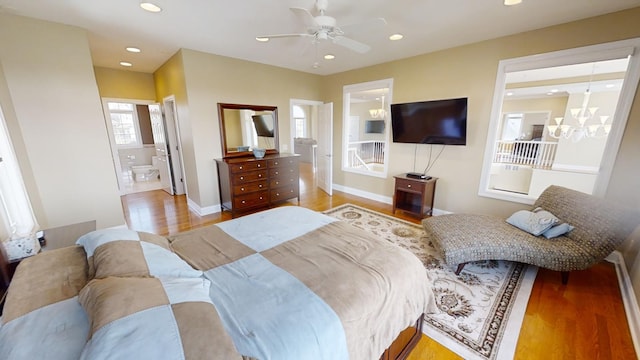 bedroom featuring light hardwood / wood-style flooring, ensuite bath, and ceiling fan with notable chandelier