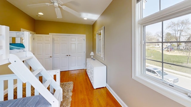 bedroom with a closet, multiple windows, wood-type flooring, and ceiling fan