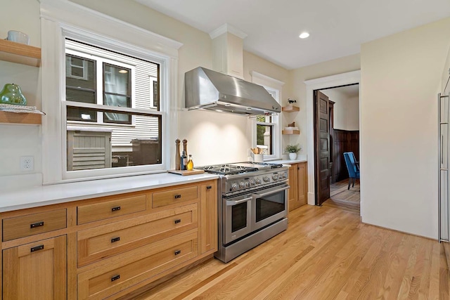 kitchen with extractor fan, range with two ovens, and light hardwood / wood-style flooring