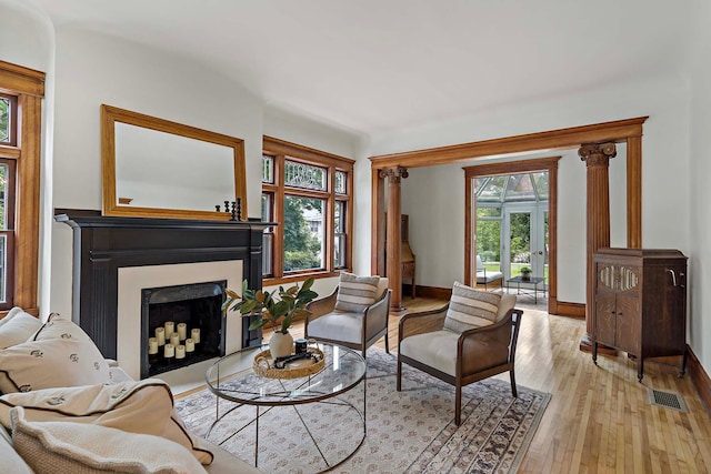 sitting room featuring ornate columns and light wood-type flooring