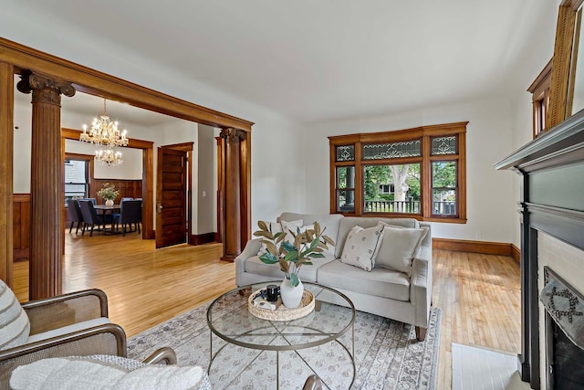 living room with wood walls, light hardwood / wood-style floors, a chandelier, and ornate columns