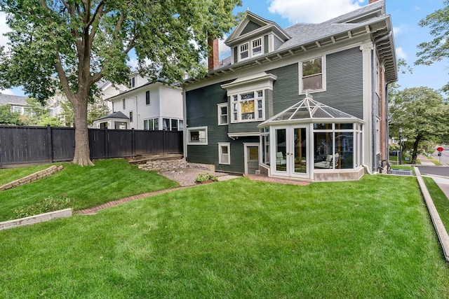 rear view of house with french doors and a lawn