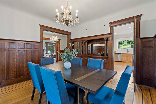 dining space with light hardwood / wood-style floors and an inviting chandelier