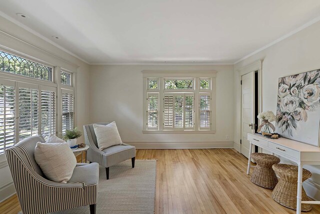 living area with light hardwood / wood-style flooring and ornamental molding