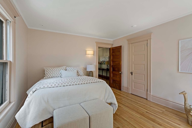 bedroom featuring multiple windows, light wood-type flooring, and crown molding