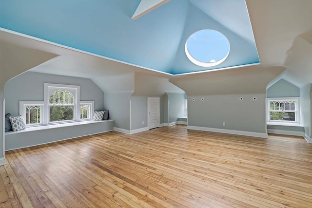 additional living space with light hardwood / wood-style floors and vaulted ceiling