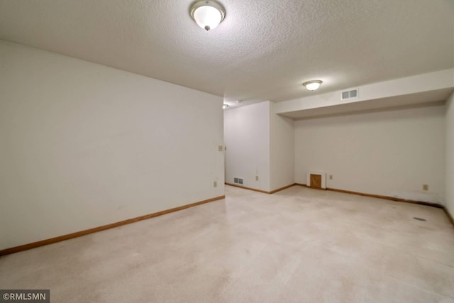 basement with a textured ceiling and light colored carpet