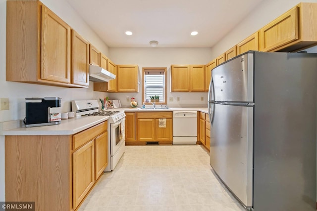 kitchen with light brown cabinets, sink, and white appliances