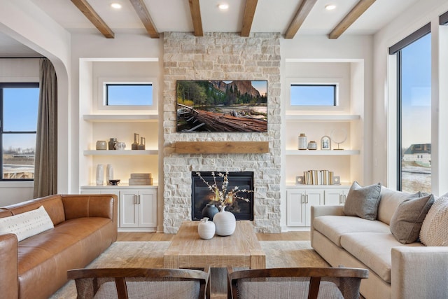 living room featuring a fireplace, built in features, beamed ceiling, and light wood-type flooring