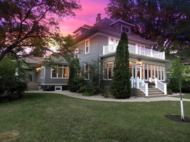 view of front of house with a balcony and a yard