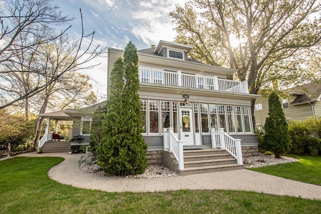 rear view of house featuring a balcony and a lawn