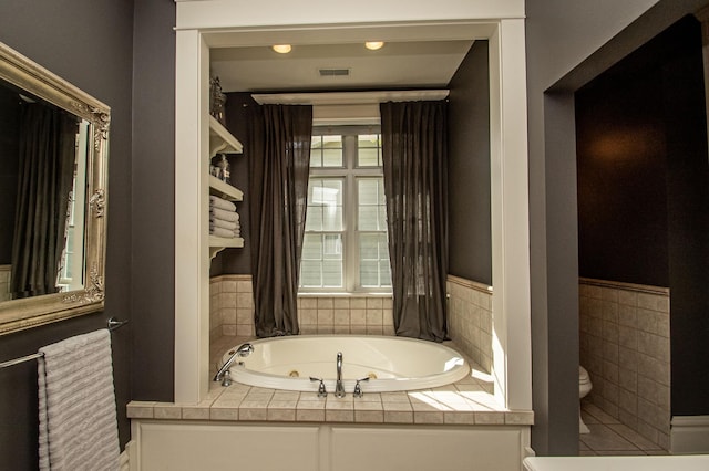 bathroom featuring tiled tub and toilet