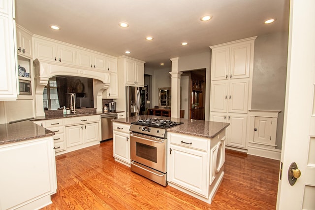 kitchen featuring white cabinets, sink, a center island, light hardwood / wood-style floors, and appliances with stainless steel finishes