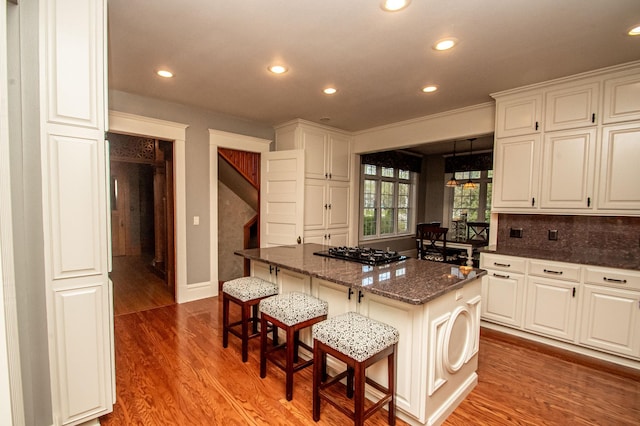 kitchen featuring white cabinetry, a center island, a breakfast bar area, and hardwood / wood-style floors