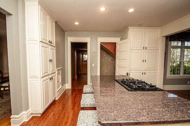 kitchen with white cabinets, dark stone countertops, hardwood / wood-style floors, and black gas cooktop