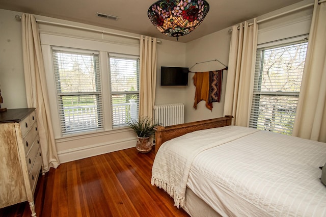 bedroom featuring dark hardwood / wood-style floors, radiator, and multiple windows