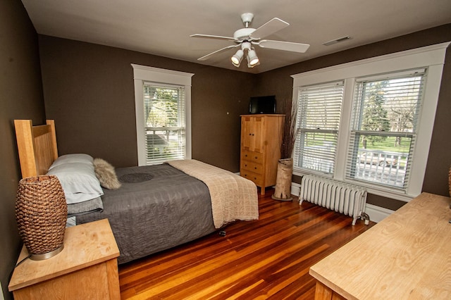 bedroom with radiator heating unit, ceiling fan, and dark hardwood / wood-style floors