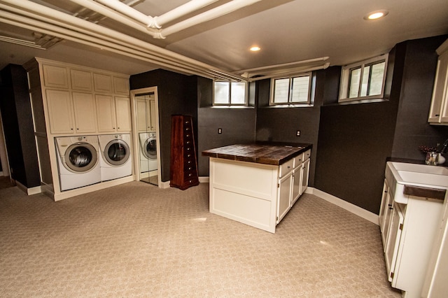 washroom with washing machine and clothes dryer, light carpet, sink, and cabinets