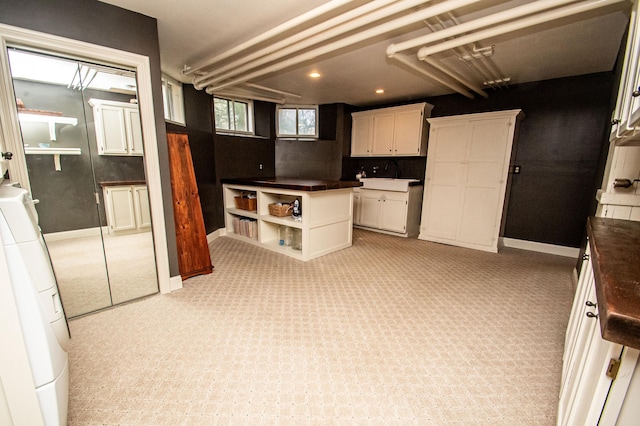 kitchen featuring white cabinets, light carpet, and washer / clothes dryer