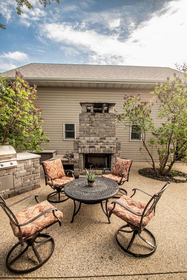 view of patio featuring an outdoor stone fireplace and area for grilling