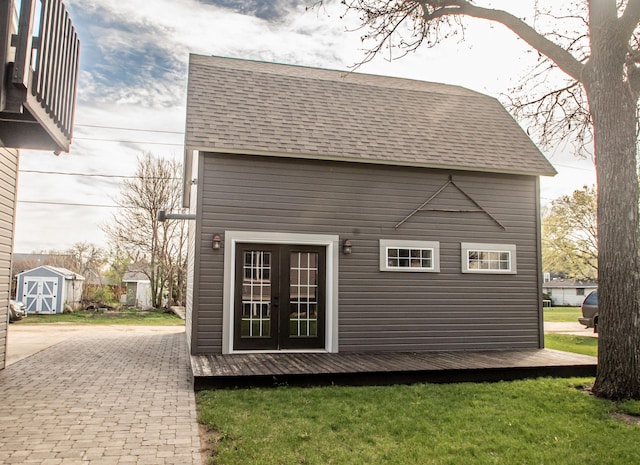 rear view of property featuring an outbuilding, french doors, and a lawn