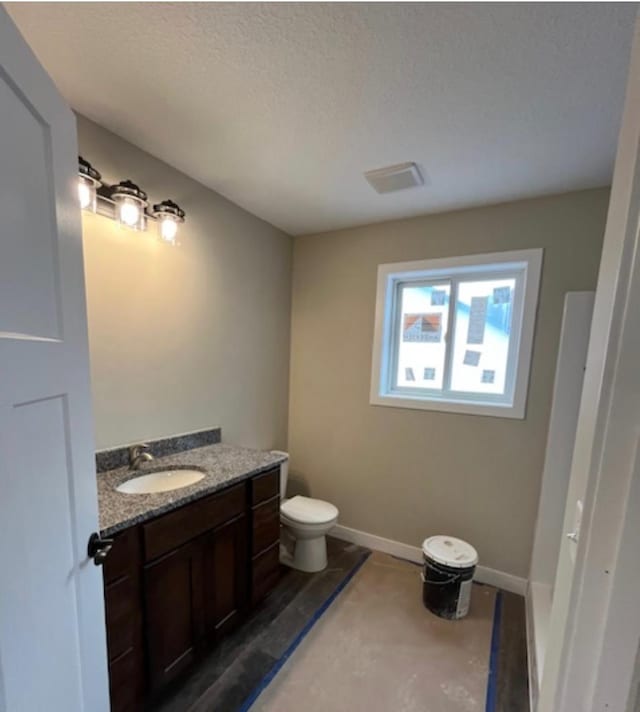 bathroom featuring concrete floors, vanity, a textured ceiling, and toilet