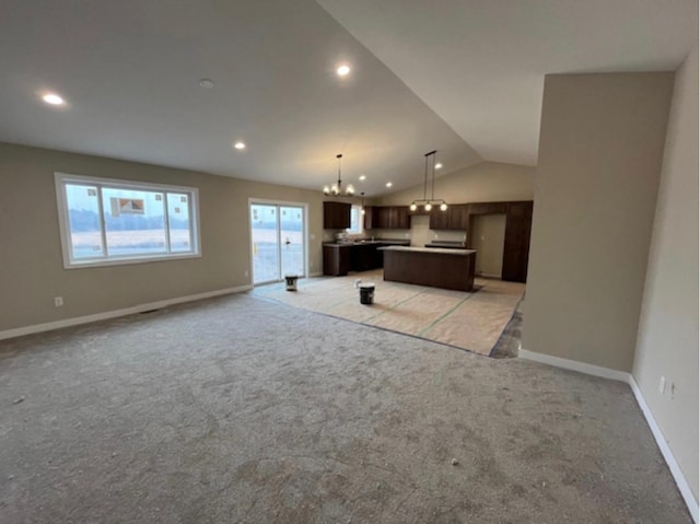 unfurnished living room featuring lofted ceiling, a chandelier, and light colored carpet