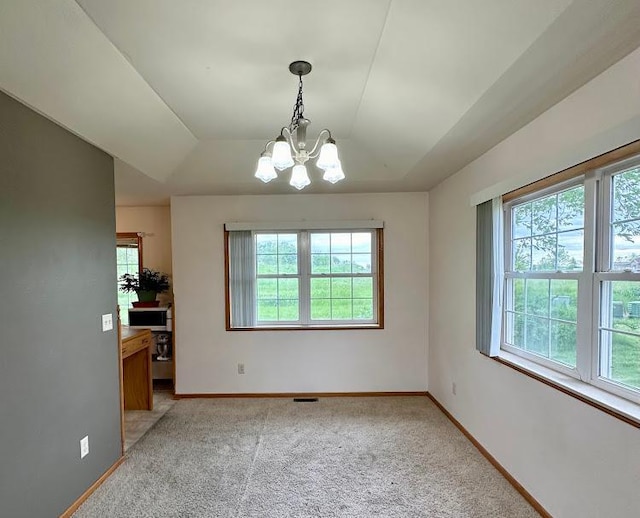 interior space featuring a healthy amount of sunlight, an inviting chandelier, and light carpet