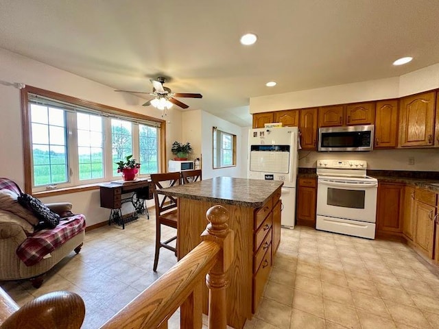 kitchen featuring a healthy amount of sunlight, white appliances, a kitchen island, and ceiling fan