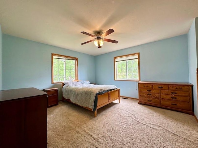 carpeted bedroom featuring multiple windows and ceiling fan