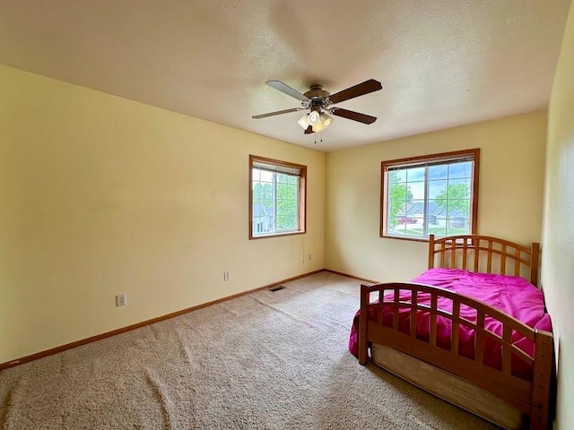 unfurnished bedroom with multiple windows, ceiling fan, and carpet floors