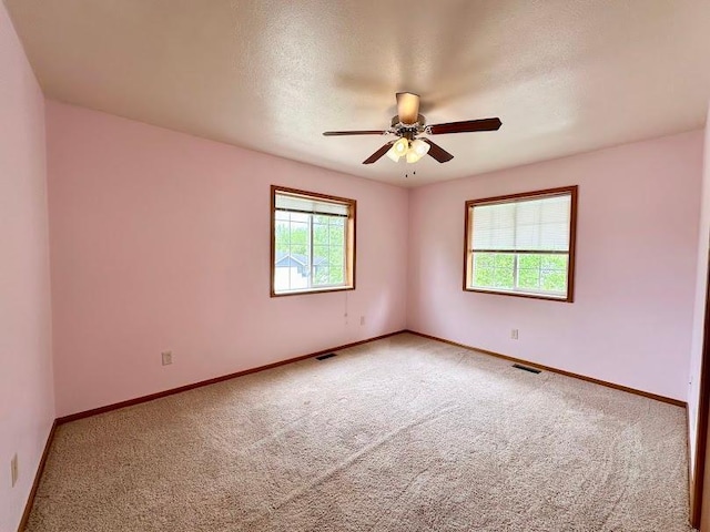 carpeted spare room featuring ceiling fan, a textured ceiling, and a healthy amount of sunlight