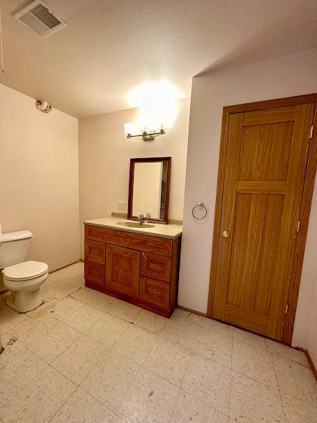 bathroom with a textured ceiling, vanity, and toilet