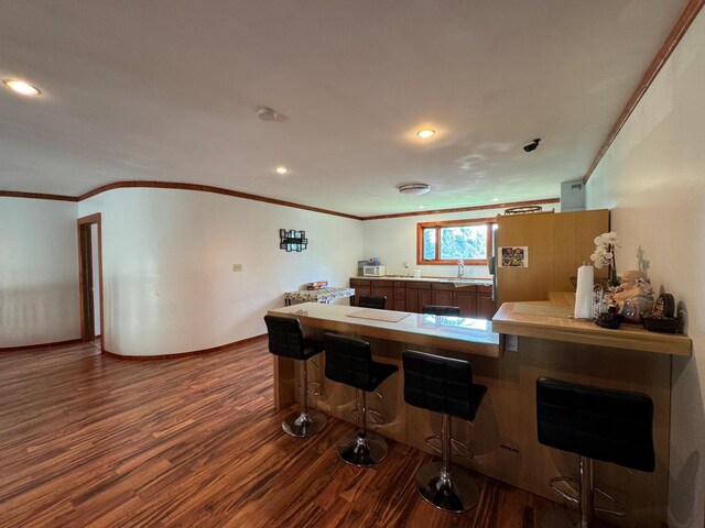 kitchen featuring a breakfast bar, sink, kitchen peninsula, white fridge, and hardwood / wood-style flooring