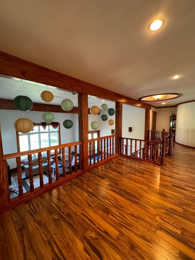 empty room featuring beam ceiling and hardwood / wood-style flooring