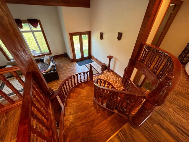 stairs with hardwood / wood-style flooring, french doors, and a towering ceiling