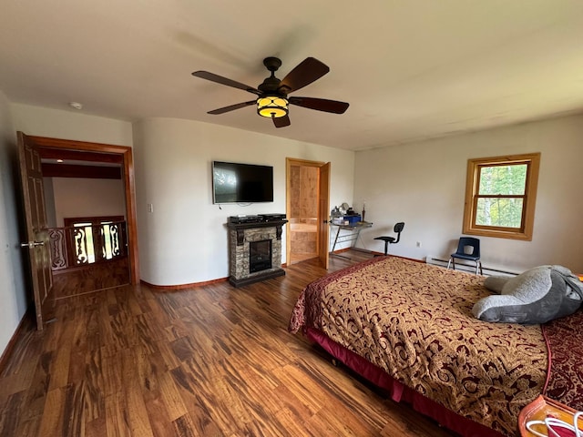 unfurnished bedroom with a ceiling fan, baseboards, dark wood finished floors, a stone fireplace, and baseboard heating