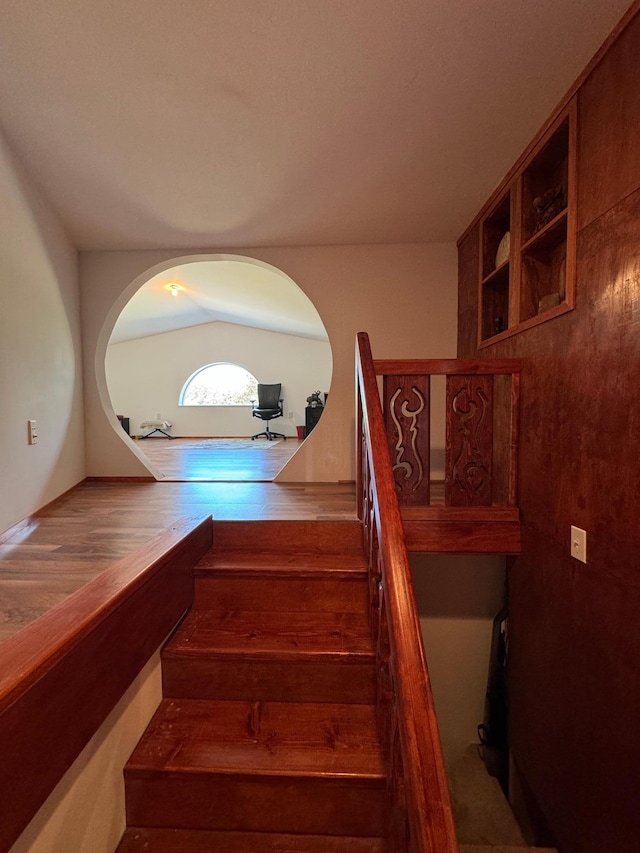 staircase with lofted ceiling and wood finished floors