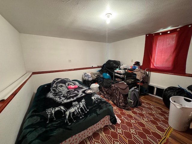 bedroom with wood finished floors and a textured ceiling