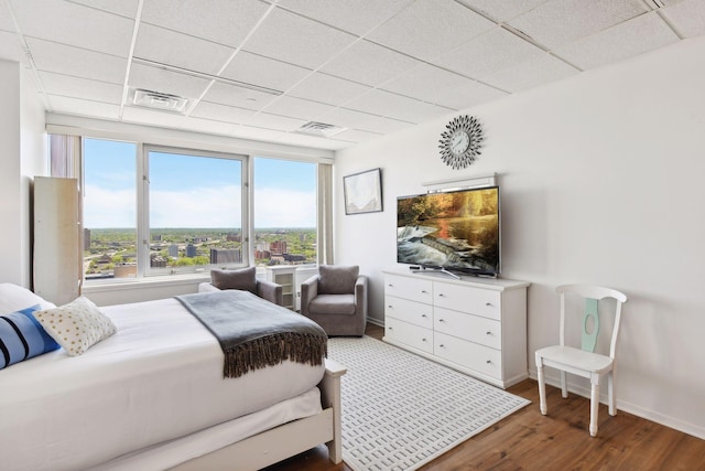 bedroom featuring a drop ceiling and wood-type flooring