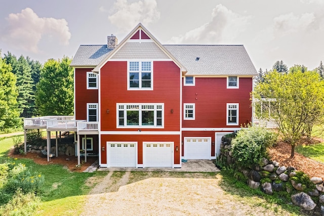 rear view of property with a garage and a deck