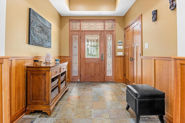 foyer with light tile patterned floors and a raised ceiling