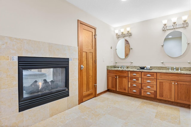 bathroom with tile patterned flooring, tile walls, dual bowl vanity, and a tile fireplace