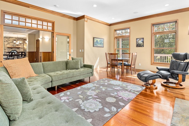 living room featuring crown molding, plenty of natural light, an inviting chandelier, and hardwood / wood-style floors