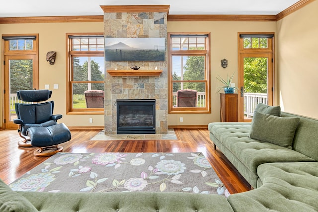 living room featuring a stone fireplace, ornamental molding, and hardwood / wood-style floors