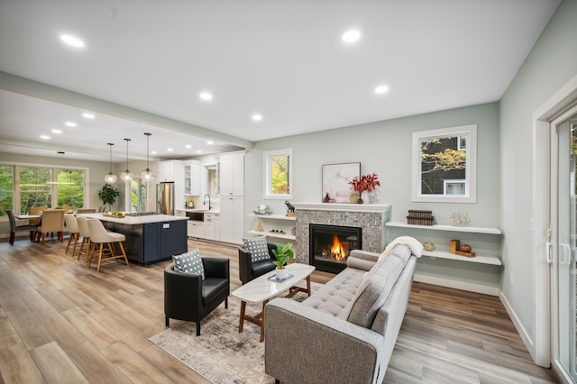 living room with a stone fireplace, sink, and light hardwood / wood-style floors